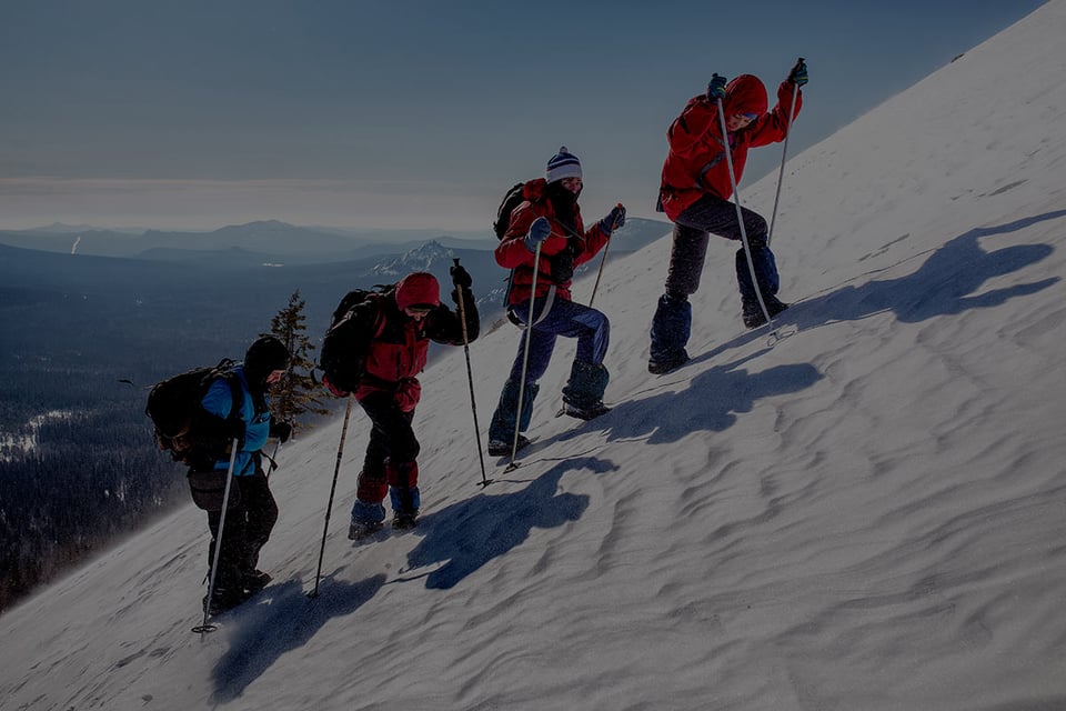 A team of climbers scaling a steep, snow-covered mountain—symbolizing the challenges of multi-entity accounting and the advantage of using purpose-built tools like Gravity Software to reach the summit efficiently