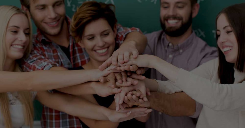 Teamwork-and-collaboration-amongst-students-with-a-laughing-group-of-diverse-young-men-and-women-standing-close-together-forming-a-stack-with-their-hands