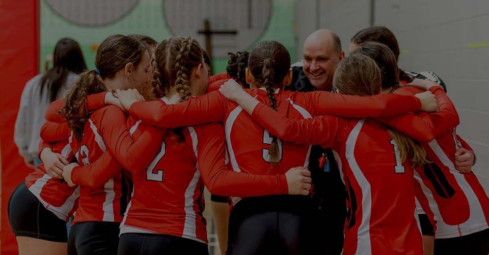 Volleyball team huddling with their coach before a match, representing collaboration and connected business applications