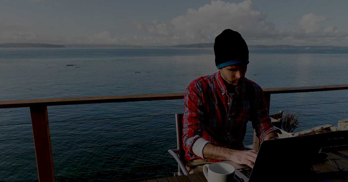 man-on-laptop-in-front-of-lake