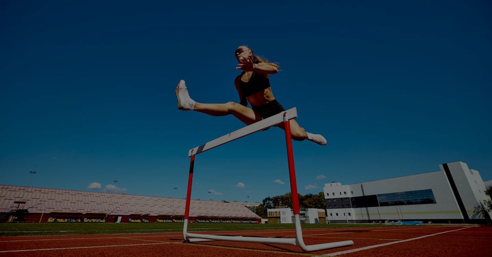 Track athlete approaching multiple hurdles representing the financial reporting and consolidation challenges organizations face as they grow.
