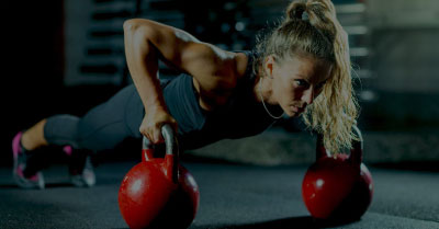 Woman athlete holding a plank with barbells, symbolizing SMB strength and control using Gravity Software’s ERP features
